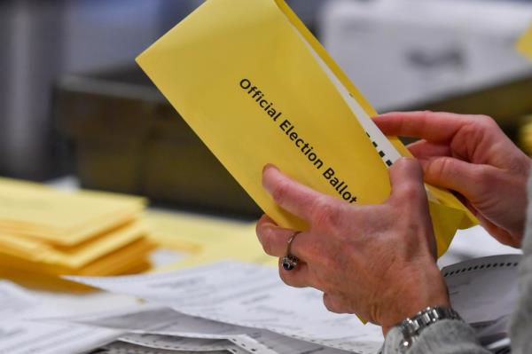 A woman takes a mail-in ballot from an envelope