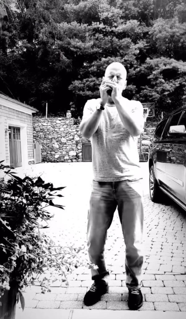 Bruce Willis playing music outside his home.