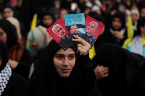 A woman holding a photo of Saleh al-Arouri. 