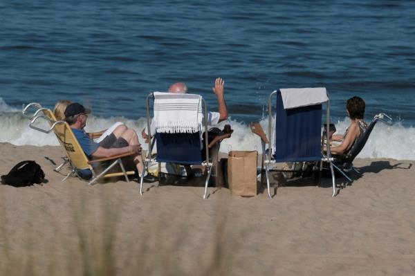 U.S. President Joe Biden waves as he sits on the beach during a visit to Rehoboth Beach, Delaware, U.S., August 13, 2023.