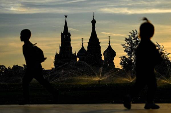 Children play in Zaryadye park in front of the Kremlin's Spasskaya tower and St Basil's cathedral during sunset in downtown Moscow on June 13, 2023.