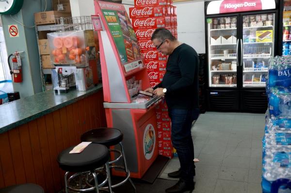 Alvaro Co<em></em>ntreras fills out a Mega Million lottery ticket at the La Esquina Tropical supermarket on March 26, 2024 in Miami, Florida.