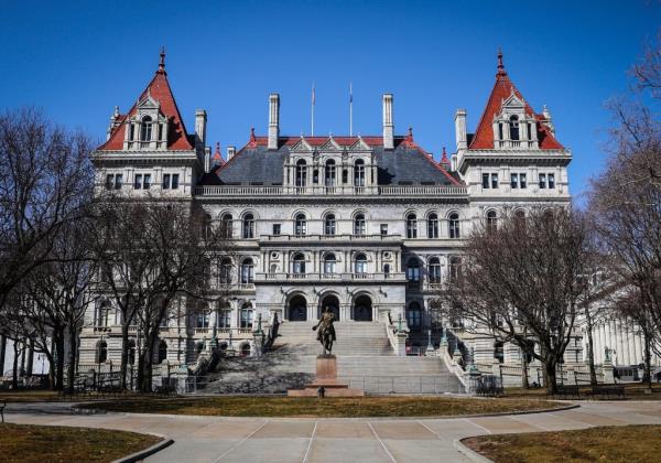 New York State Capital Building in Albany, with large white structure, red roofs, and statue of a man