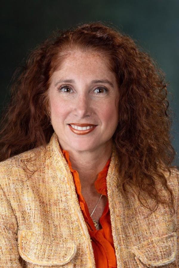 Laura Feijoo in professio<em></em>nal photo wearing teed blazer and orange blouse.