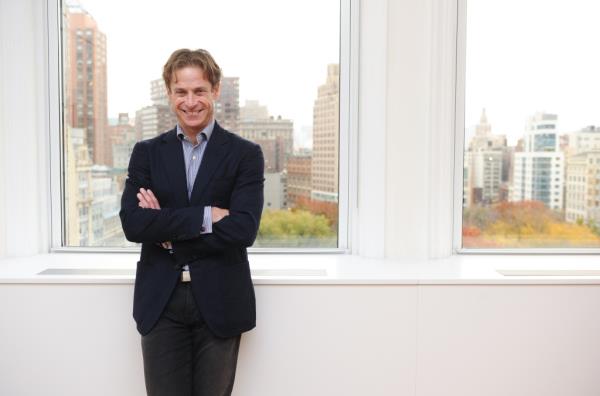 Billy Macklowe in front of a window showing Manhattan buildings