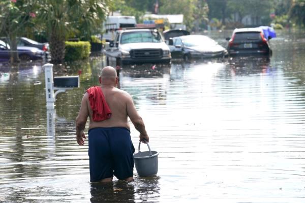 A man walking through a flooded street in Fort Lauderdale, Florida on April 14, 2023.