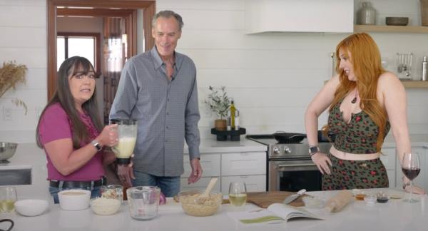 Joe Gow stands in the kitchen with his wife Carmen Wilson and an adult film star.