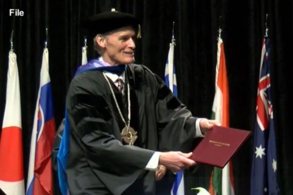 University chancellor Joe Gow hands out a diploma.