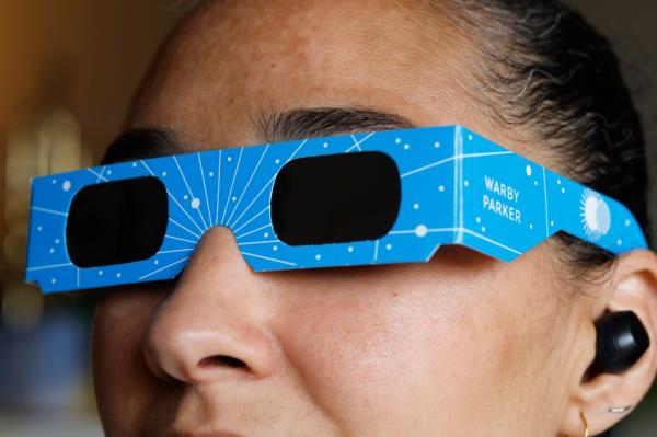 Woman wears eclipse viewing glasses by Warby Parker