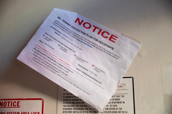 A notice announcing a tenant protection plan is seen in the building's vestibule.