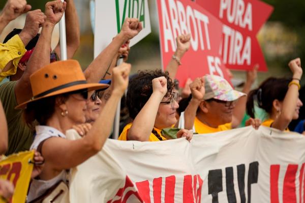 A group holds signs as they protest against buoys that are set to be deployed in the Rio Grande, Friday, July 7, 2023