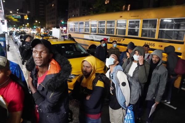 Migrants get off a school bus that transported them to the NYPD police academy to spend the night.