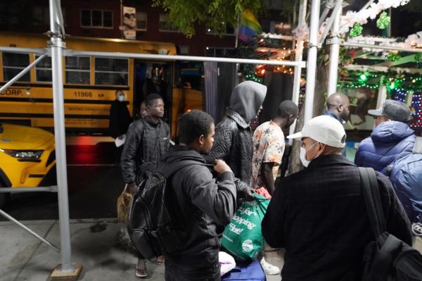 Migrants get off a school bus that transported them to the NYPD police academy to spend the night.