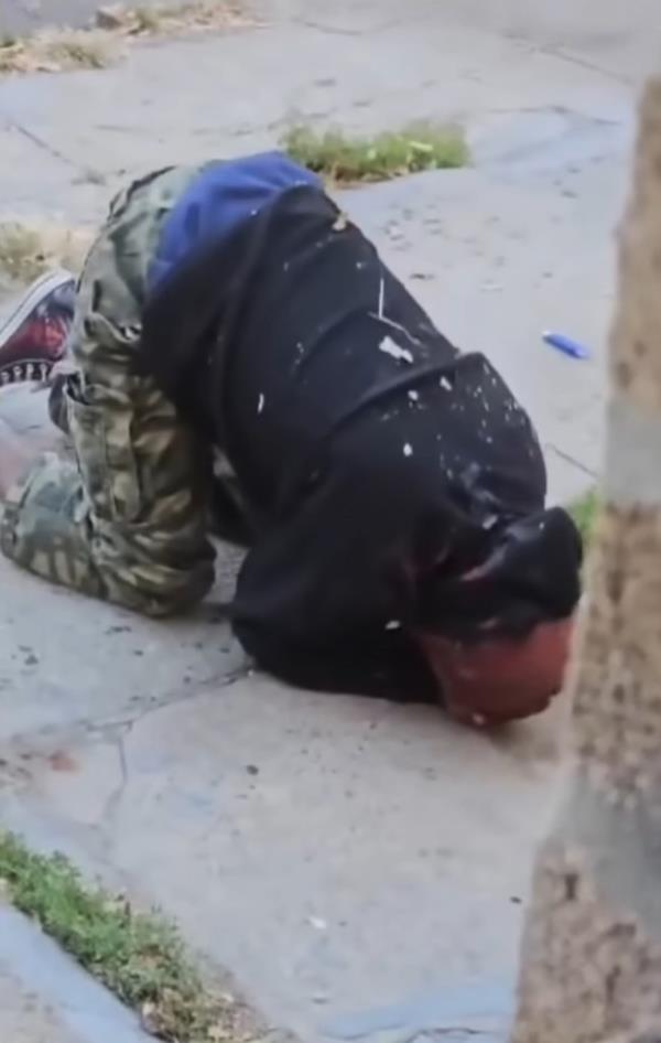 A screenshot showing Buckshot on the ground, holding his head in both hands.