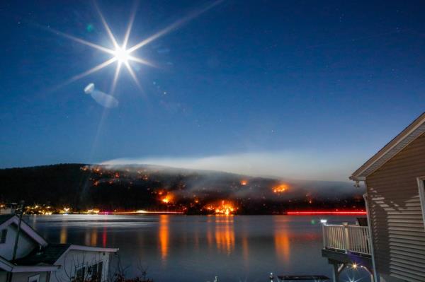  Smoke rises from the Jennings Creek Wildfire as the moon rises over Greenwood Lake on November 13, 2024 in Greenwood Lake, New York