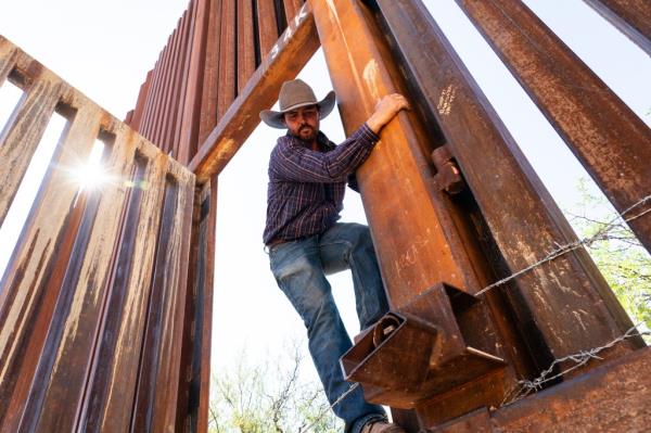 Arizona rancher Tyler Klump climbs through an open floodgate in the border wall.