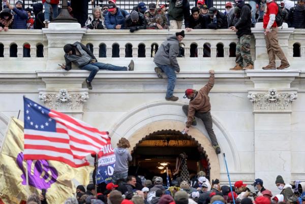January 6 2021 rioters climbing the walls of the Capitol.