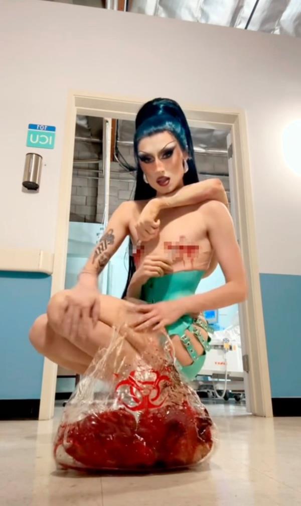 A photo of Gottmik, a trans man drag queen, staring at the camera while wearing a latex skirt.