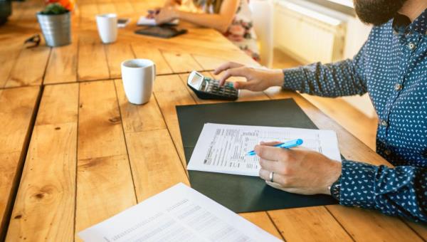A man fills out tax docu<em></em>ments with a pen in a office setting.