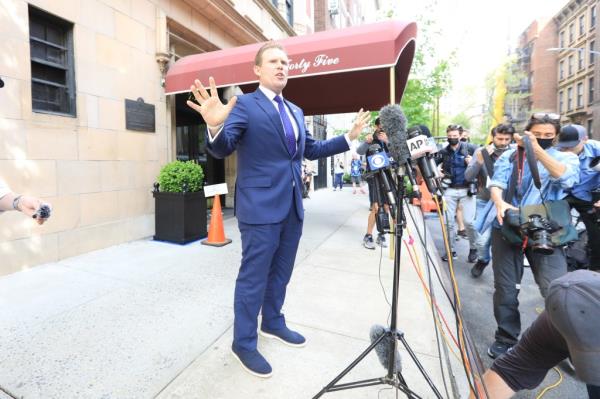 Andrew Giuliani, son of Rudy Giuliani, addressing the media in a suit outside of his father's Manhattan apartment post FBI raid