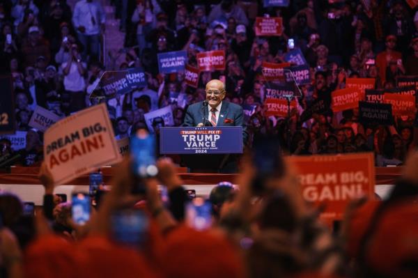 Former NYC mayor Rudy Giuliani standing at a podium during a campaign rally held by Do<em></em>nald Trump at Madison Square Garden, with a crowd of people behind him.