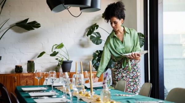 A woman setting a dining room table