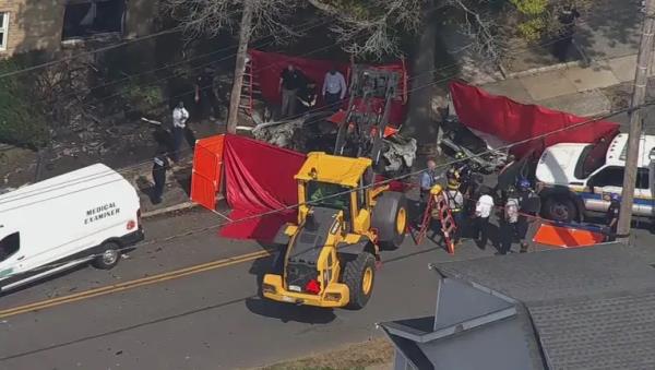 Aerial view from SkyFOX of emergency crews at a scene in White Plains wher<em></em>e a car has crashed into a tree with a co<em></em>nstruction vehicle and people around it.