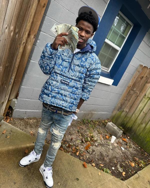 Quando Ro<em></em>ndo holding mo<em></em>ney in front of a house after federal agents arrest co<em></em>nnection to cousin's murder