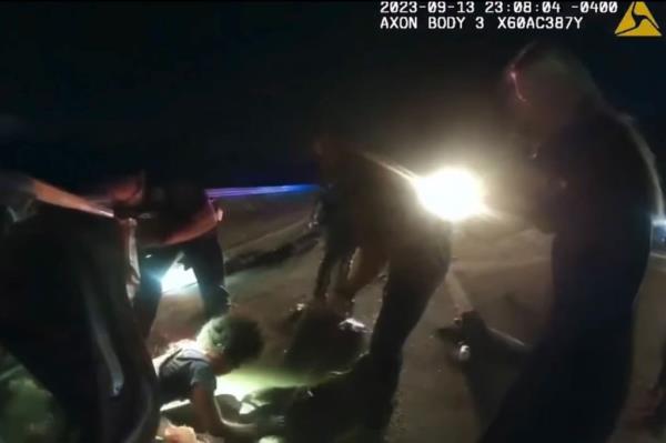 The teenager can be seen appearing from the small space officers and bystanders opened up for him.