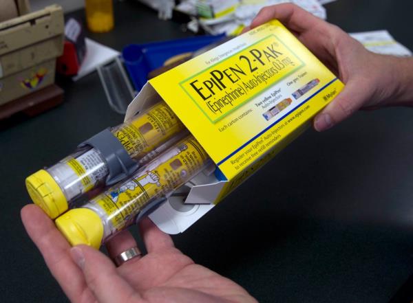 In this July 8, 2016, file photo, a pharmacist holds a package of EpiPens epinephrine auto-injector, a Mylan product, in Sacramento, California