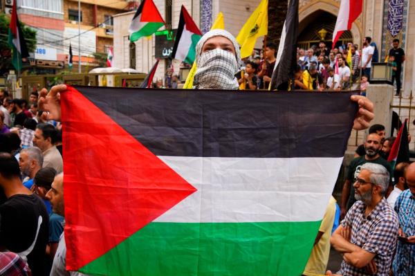 A Hezbollah supporter holds a Palestinian flag during a rally in solidarity with the Palestinian people in Gaza, in the southern Beirut suburb of Dahiyeh, Lebanon, Sunday, Oct. 8, 2023. 