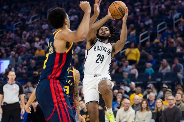 Cam Thomas (24) shoots over Golden State Warriors forward Andrew Wiggins (22) during the first half at Chase Center. 