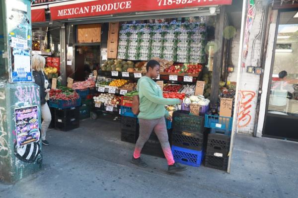 Female perp in green sweater walking in front of the store wher<em></em>e she committed the crime