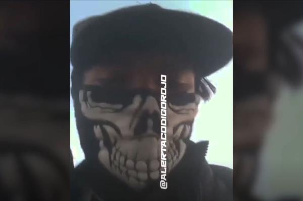The video shows an armed cartel member in a skull mask leading the teens — ages 14 to 18 — who are dressed with black hoods over their faces obscuring their view and their hands tied behind their backs.