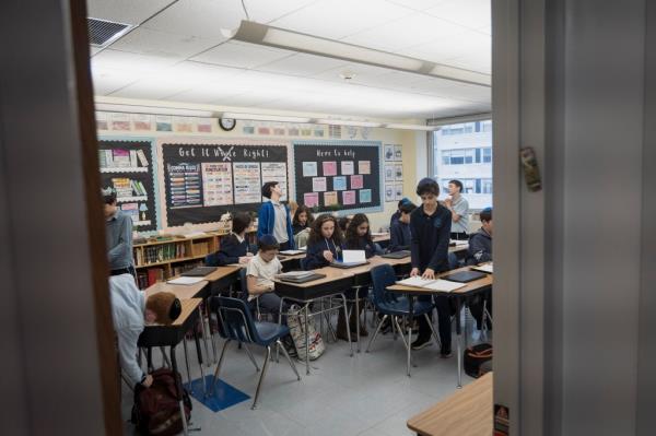 A group of people sitting and standing inside a classroom of Rabbi Arthur Schneier Park East Day School in New York.