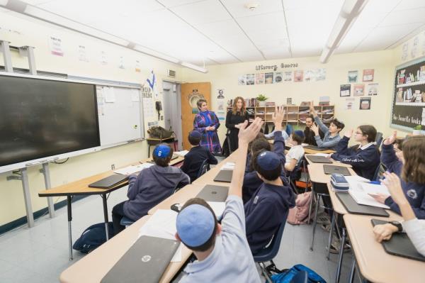 A woman, Debbie Rochlin, stands in a classroom of a Jewish private school with Rabbi Arthur Schneier Park East Day School in New York City.