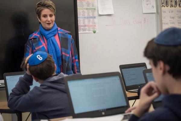 A woman, Debbie Rochlin, stands in front of a whiteboard with students at Rabbi Arthur Schneier Park East Day School in NYC. Photo by Stefano Giovannini.