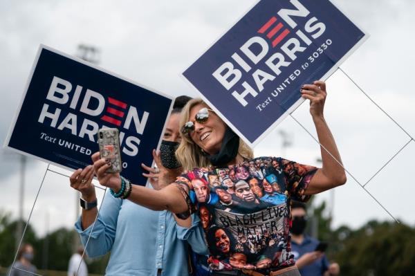 Two women holding Biden/Harris lawns signs take a selfie at a rally with Democratic Senate candidates Rev. Raphael Warnock and Jon Ossoff.