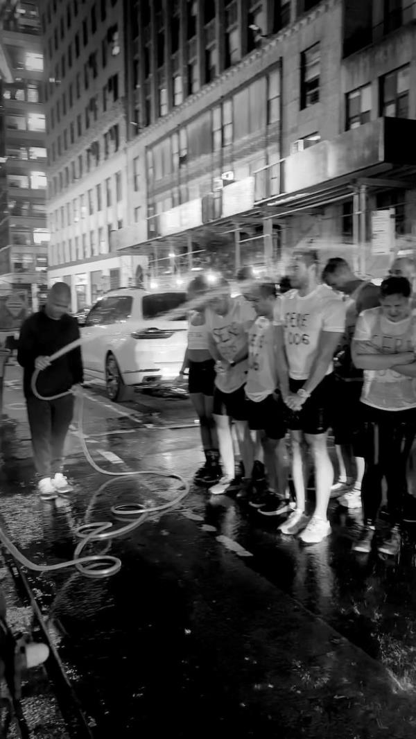 Screenshot from social media video shows workout participants getting sprayed by hose during challenge.