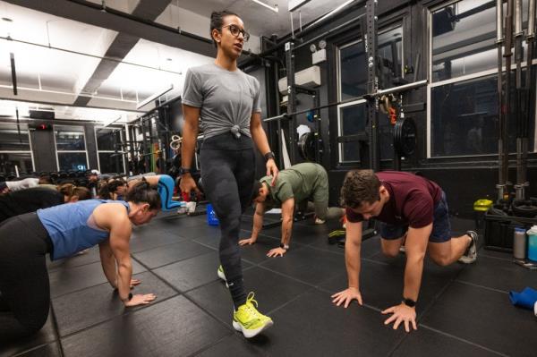 Ruben Belliard, founder of The Training Lab in Midtown and Operation Iraqi Freedom Marine veteran, poses in gym as clients workout behind him.