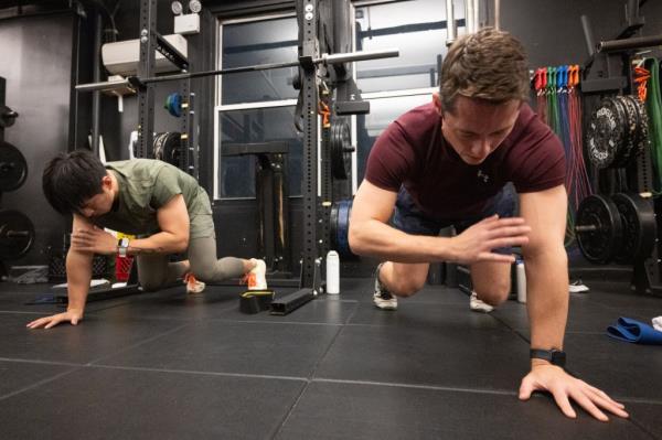 Clients at the training lab on the floor doing one-handed planks seen from floor level.