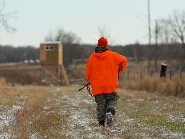 A photo of a hunter in orange walking in the direction of a lookout.