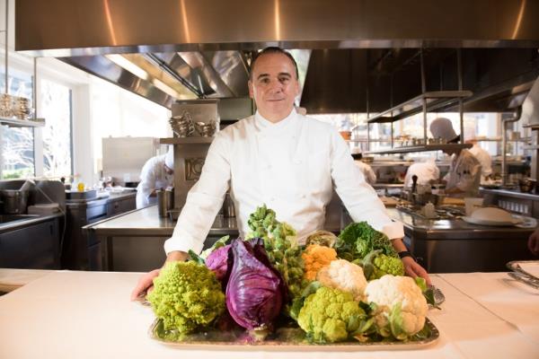 Chef Jean-Georges Vo<em></em>ngerichten in his restaurant, standing behind a tray of vegetables