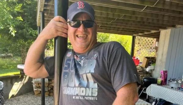 Moo<em></em>ney is pictured smiling in his backyard wearing a New England Patriots t-shirt and a Boston Red Sox hat.