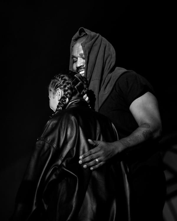 Kanye smiling onstage, hugging his daughter. 