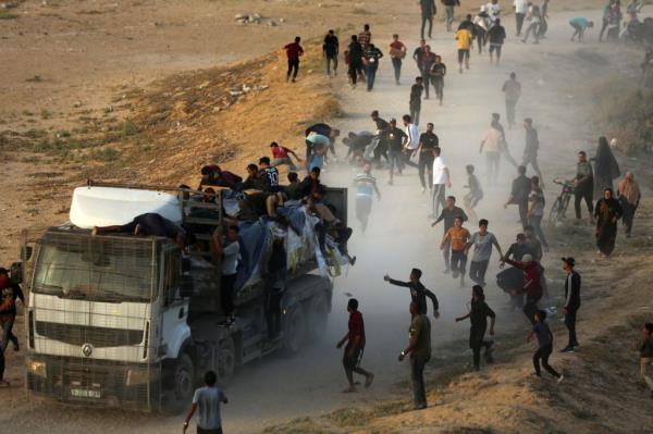 Palestinians are grabbing aid from a truck that is being delivered into Gaza through a U.S.-built pier, amid the o<em></em>ngoing co<em></em>nflict between Israel and the Palestinian Islamist group Hamas, as seen from central Gaza Strip, on May 18, 2024.