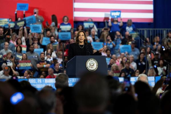 Democratic presidential nominee Kamala Harris speaking at a rally in Harrisburg, Pennsylvania, with a crowd of people behind her.