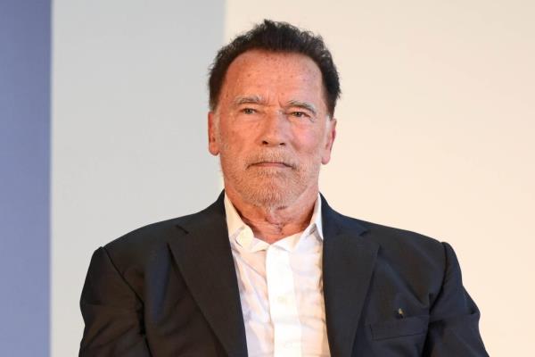 Arnold Schwarzenegger speaking on stage receiving ho<em></em>norary doctorate at Hertie School, Berlin in a suit.