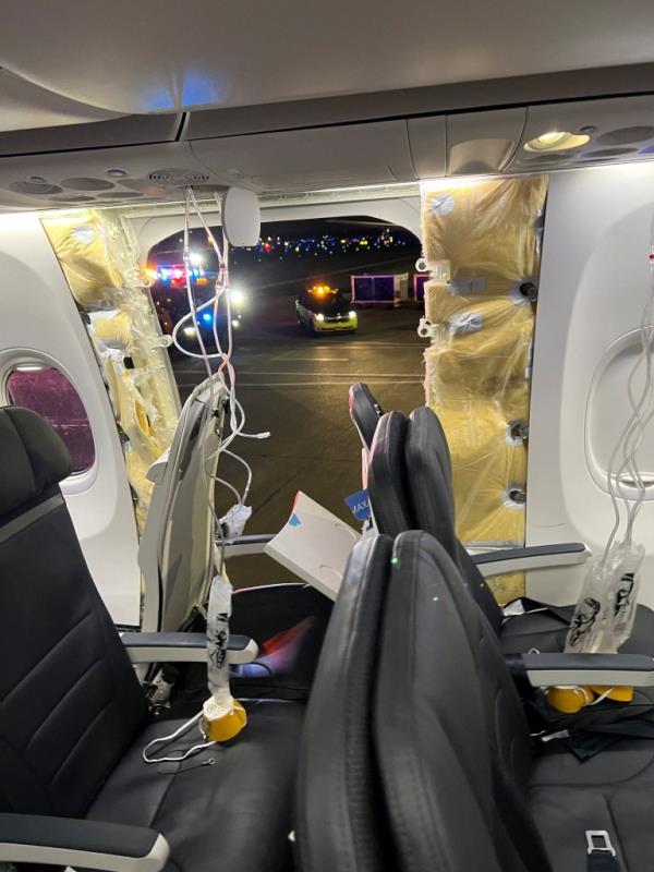 Passenger oxygen masks hang from the roof next to a missing window and a portion of a side wall of an Alaska Airlines Flight 1282, which had been bound for Ontario, California and suffered depressurization soon after departing, in Portland, Oregon, 
