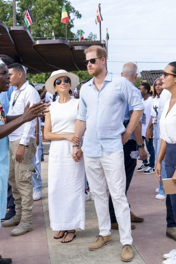 Prince Harry and Duchess Meghan of Sussex holding hands while exploring San Basilio de Palenque in Colombia